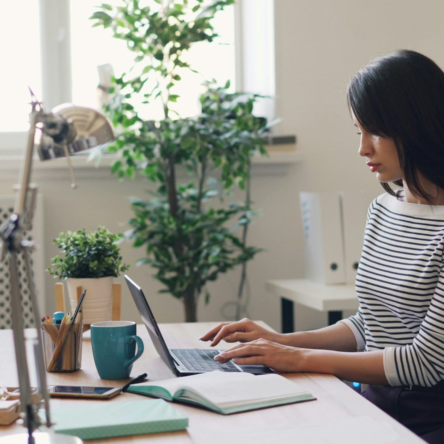 une femme assise à un bureau tape sur le clavier d’un ordinateur portable